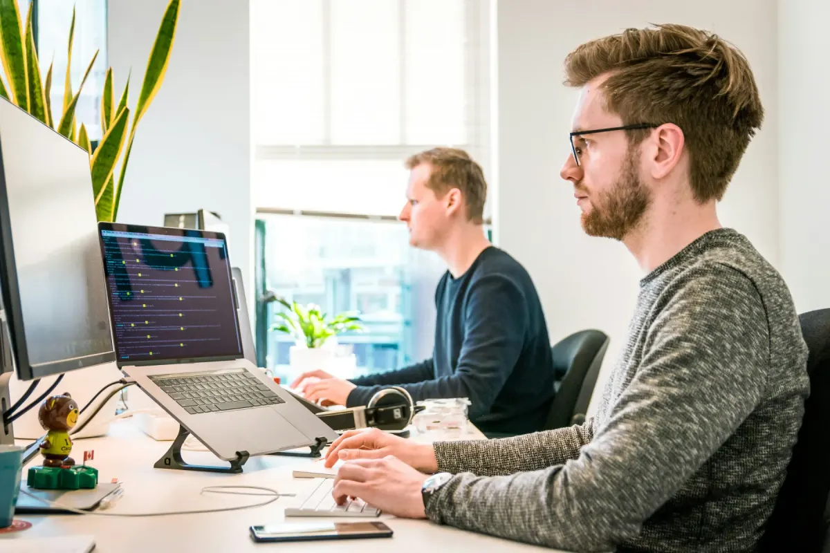 Two developers at work at their screens in a bright office