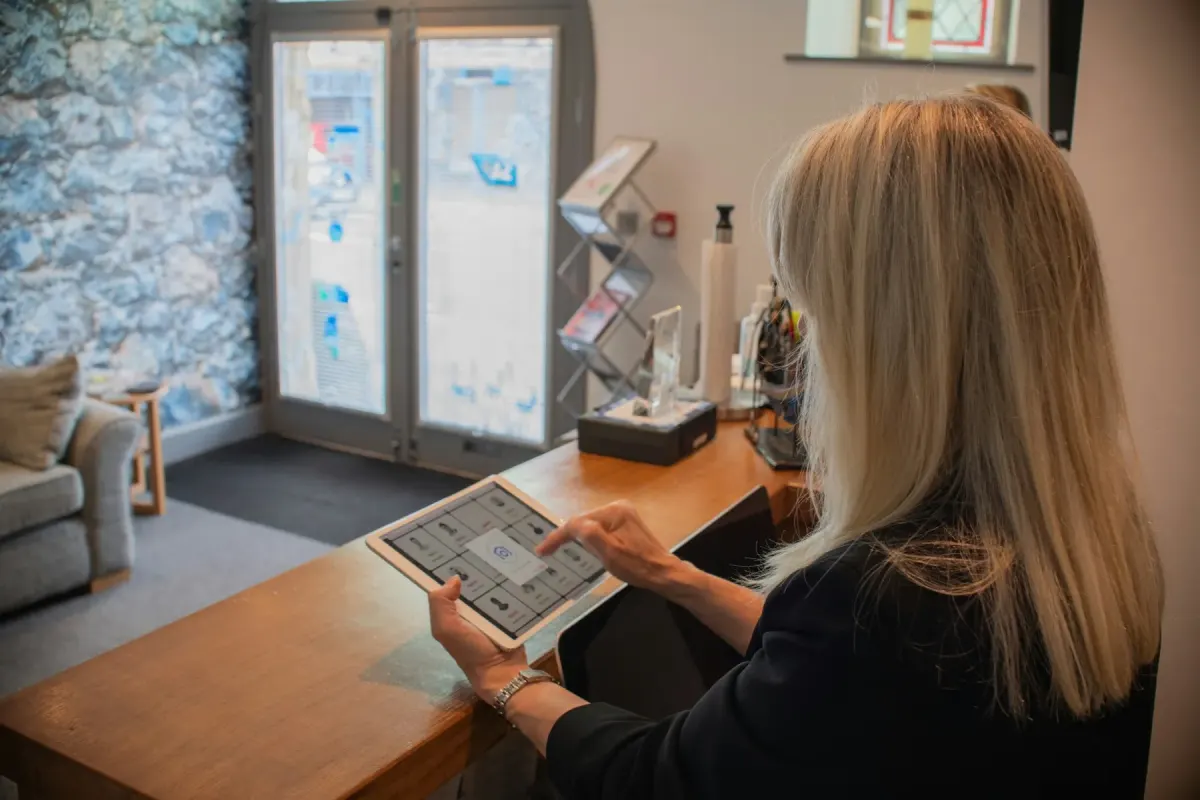 A visitor checking in on a tablet at a reception counter, with the waiting area behind