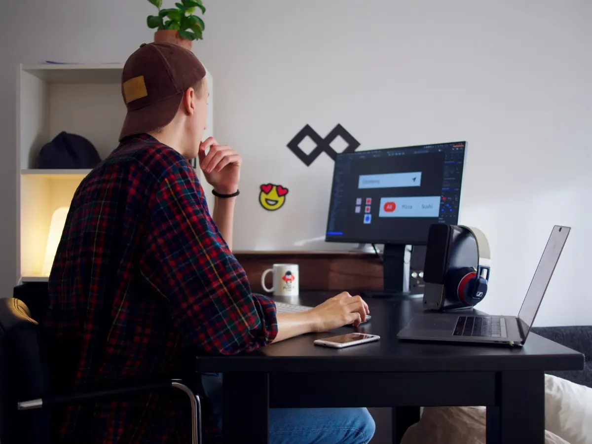 A designer working on an app interface at a desktop monitor in a small home office